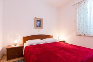 - une chambre avec un lit rouge et 2 tables de chevet dans l'établissement Apartments with a parking space Krk - 15331, à Krk