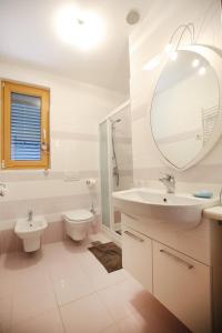ein Badezimmer mit einem Waschbecken, einem WC und einem Spiegel in der Unterkunft Holiday house with a swimming pool Zadar - Diklo, Zadar - 15336 in Zadar
