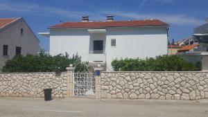 赫瓦尔Apartments and rooms with parking space Hvar - 15378的白色的房子,有石墙和围栏