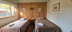 two beds in a room with wooden walls at Posada Paso Mayer in Villa O'Higgins