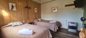 a hotel room with two beds and a television at Posada Paso Mayer in Villa O'Higgins