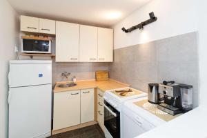 a kitchen with white cabinets and a white refrigerator at Holiday house with WiFi Novi Vinodolski - 15397 in Novi Vinodolski