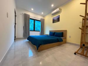 Schlafzimmer mit einem Bett mit blauer Bettwäsche und einem Fenster in der Unterkunft Mường Sang Farmstay in Mộc Châu
