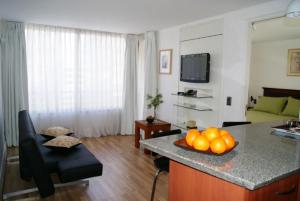 a kitchen and living room with a table with oranges on a counter at Lobato Apartments in Santiago