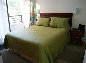 - une chambre avec un grand lit doté de draps verts et une fenêtre dans l'établissement Lobato Apartments, à Santiago
