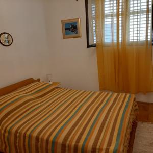 ein Schlafzimmer mit einem gestreiften Bett und einem Fenster in der Unterkunft Apartments by the sea Brist, Makarska - 15443 in Podaca