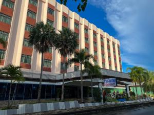 a large building with palm trees in front of it at River Grand Hotel in Hat Yai
