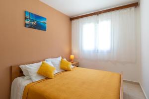 1 dormitorio con 1 cama con sábanas amarillas y ventana en Family friendly house with a parking space Prizba, Korcula - 15468, en Prizba