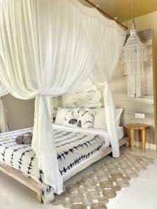 sypialnia z łóżkiem z baldachimem i białymi zasłonami w obiekcie Incense Impossible Beach-Adults Only w mieście Uluwatu