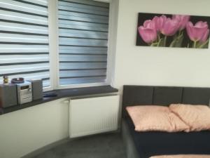 a room with a couch and a window with pink tulips at Viktoria in Ełk