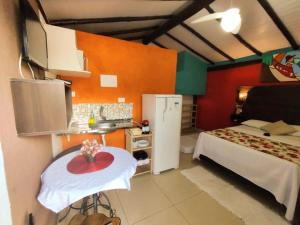 a bedroom with a bed and a kitchen with a table at Chalé de Charme MANDOMAI - Suítes com Cooktop e Chalé Charmoso com Cozinha in Ilhabela