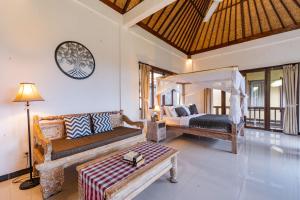 a room with a bedroom with a bed and a couch at The Dayuh Ubud in Ubud