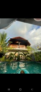 a building with a swimming pool in front of a house at Swara Homestay 2 in Nusa Lembongan