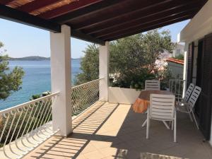 a balcony with a table and chairs and the ocean at Apartments by the sea Kaprije - 15567 in Kaprije