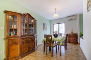 a dining room with a table and chairs and a cabinet at Apartments by the sea Mali Losinj (Losinj) - 15576 in Mali Lošinj