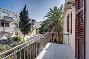 einen Balkon mit einem Zaun und Palmen in der Unterkunft Apartments by the sea Mali Losinj (Losinj) - 15576 in Mali Lošinj