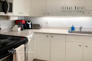 a kitchen with white cabinets and a sink and a stove at New Aloha Ilikai 1free Parking in Honolulu