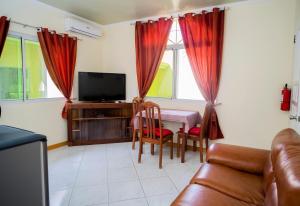ein Wohnzimmer mit einem Tisch, Stühlen und einem TV in der Unterkunft Alona Austria Resort in Panglao