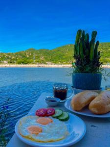 a breakfast of eggs and bread on a table by the water at Chau Gia Hotel in Vĩnh Hy
