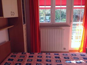 a bedroom with a bed and a window with red curtains at Apartments with a parking space Risika, Krk - 15609 in Vrbnik