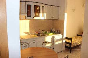 a kitchen with white cabinets and a table and a sink at Apartments with a parking space Gradac, Makarska - 15628 in Gradac