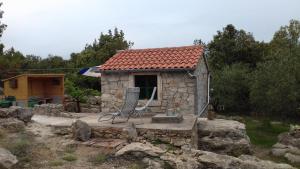 a small stone house with a chair in front of it at Secluded holiday house Pasman - 15649 in Pašman