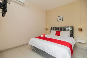 a bedroom with a large white bed with red accents at RedDoorz near Transmart Kalimalang in Jakarta