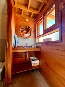 een houten badkamer met een wastafel en een raam bij Mandala Tiny House, Traslasierra. in Yacanto