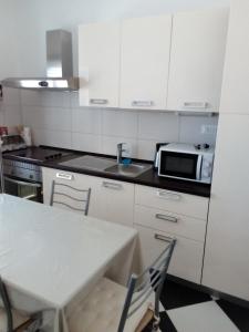 a kitchen with a table and a sink and a microwave at Apartments with a swimming pool Sevid, Trogir - 15664 in Sevid