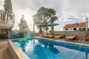 a swimming pool with tables and chairs next to a house at Family friendly apartments with a swimming pool Sutivan, Brac - 15665 in Sutivan
