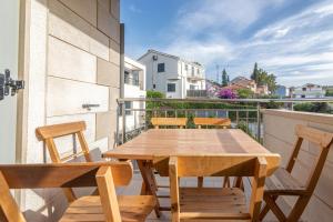 a wooden table and chairs on a balcony at Family friendly apartments with a swimming pool Sutivan, Brac - 15665 in Sutivan