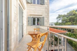 a balcony with a wooden table and chairs on it at Family friendly apartments with a swimming pool Sutivan, Brac - 15665 in Sutivan