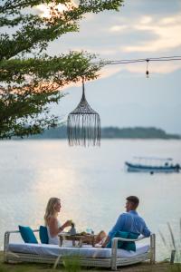 吉利特拉旺安的住宿－海濱別墅度假酒店，坐在水边桌子上的男人和女人