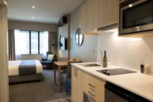 a room with a kitchen and a bedroom with a bed at Quest 256 Lambton in Wellington