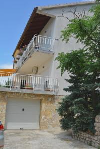 a white building with a garage and a balcony at Apartments with a parking space Smrika, Kraljevica - 15709 in Šmrika