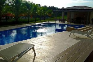 ein Pool mit zwei Stühlen und einer Bank daneben in der Unterkunft Apartamento de 1 recamara en Panama Pacifico in ArraijÃ¡n