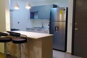 - un réfrigérateur en acier inoxydable dans une cuisine avec deux tabourets de bar dans l'établissement Apartamento de 1 recamara en Panama Pacifico, à ArraijÃ¡n