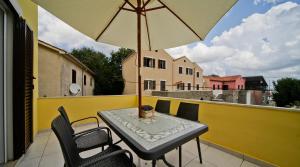 a table and chairs on a balcony with an umbrella at Apartments by the sea Nerezine, Losinj - 15778 in Nerezine