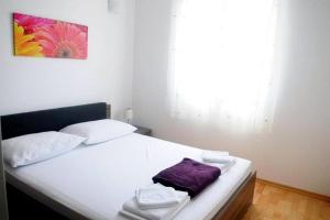 sypialnia z białym łóżkiem z fioletowym ręcznikiem w obiekcie Apartments with a parking space Klenovica, Novi Vinodolski - 15987 w mieście Klenovica
