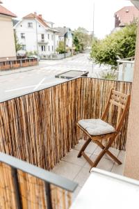 a wooden chair sitting on a balcony with a fence at White Apartment in Ljubljana