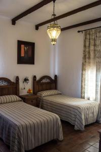 a bedroom with two beds and a chandelier at Casa Rural Sierra Tórtola 2 in Hinojales