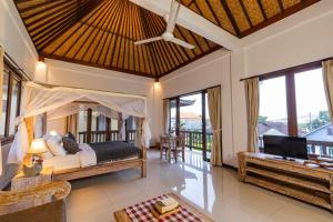 a bedroom with a bed and a living room at The Dayuh Ubud in Ubud