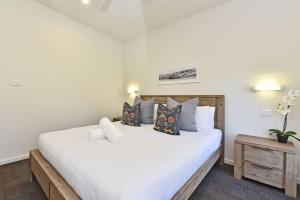 um quarto com uma grande cama branca com almofadas em Ironbark Hill Villa 1 Tyrian em Pokolbin