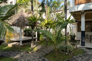 ein Innenhof mit einer Bank und Palmen in der Unterkunft The Chillhouse Canggu by BVR Bali Holiday Rentals in Canggu