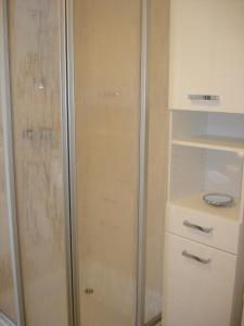 La salle de bains est pourvue d'une douche avec une porte en verre. dans l'établissement Grachtenstube, à Greetsiel