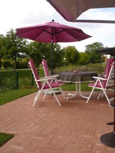 2 chaises et une table avec un parasol dans l'établissement Grachtenstube, à Greetsiel