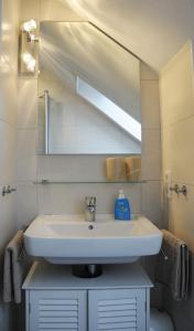 La salle de bains est pourvue d'un lavabo blanc et d'un miroir. dans l'établissement An den Zwillingsmühlen, à Greetsiel