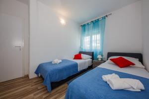 1 dormitorio con 2 camas y almohadas azules y rojas en Apartments with a parking space Kastel Stari, Kastela - 16087, en Kaštela
