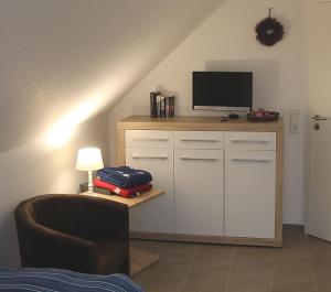 ein Wohnzimmer mit einem TV und einem Stuhl in der Unterkunft Windrose in Greetsiel