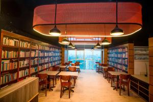 une bibliothèque avec des tables, des chaises et des étagères dans l'établissement Royal Raj Hotel, à Râjshâhî